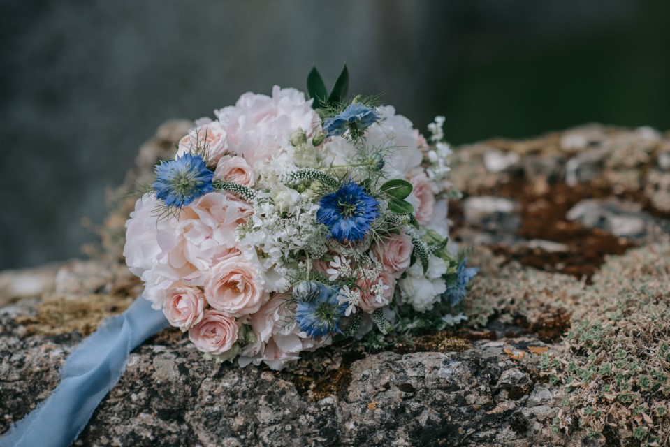 A pink and blue bouquet on a wall at Westenhanger Castle with E-Lope and Fleur Challis Photography