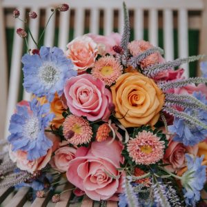 Candy coloured bouquet on a wooden deck chair at The Castle Westehanger Kent with Fleur Challis Photography and E-Lope